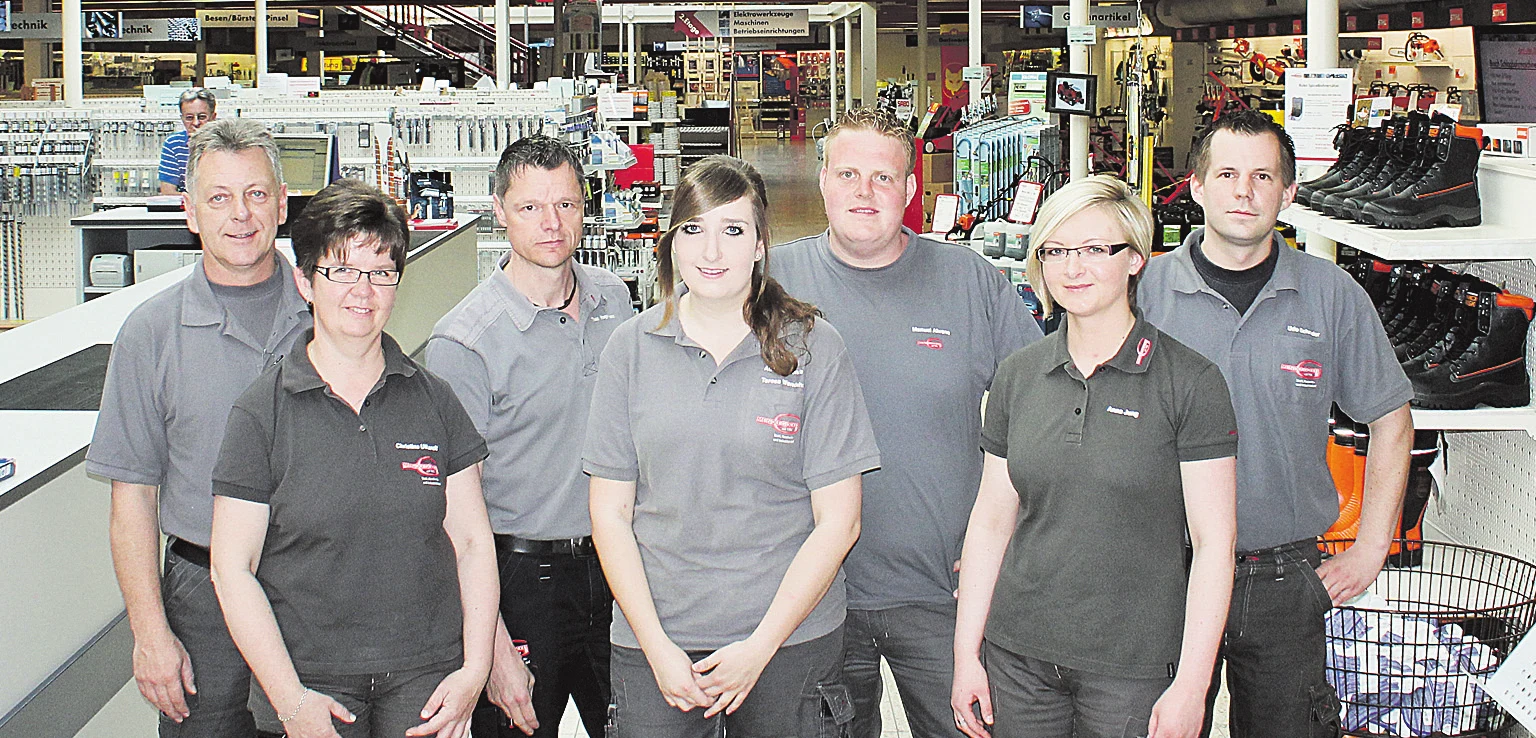 Das Team des Abholmarkts in grauen Poloshirts zwischen den Regalen