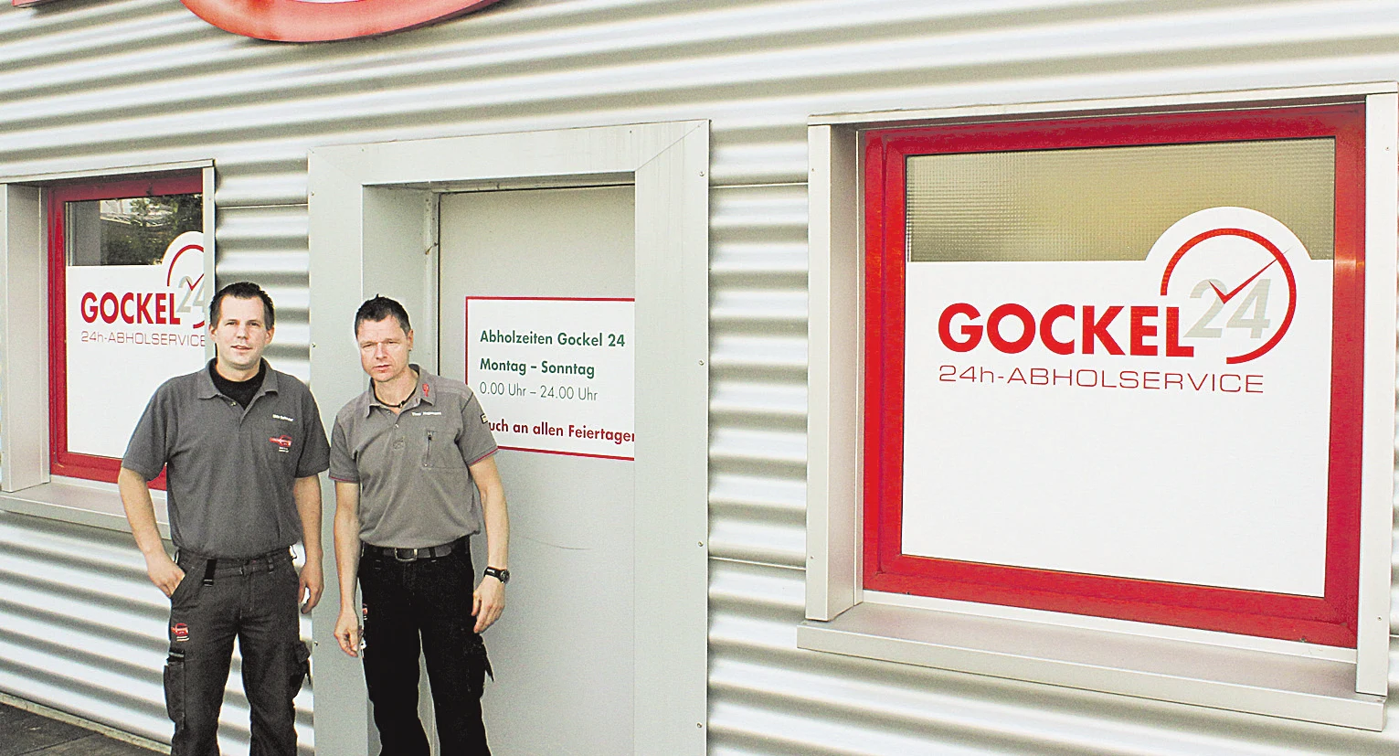 Eingang zum Gockel 24h-Abholservice mit zwei Mitarbeitern vor der Tür