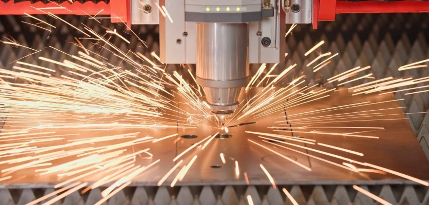 Laserschneidkopf über einer Blechtafel, Funken sprühen beim Schneiden