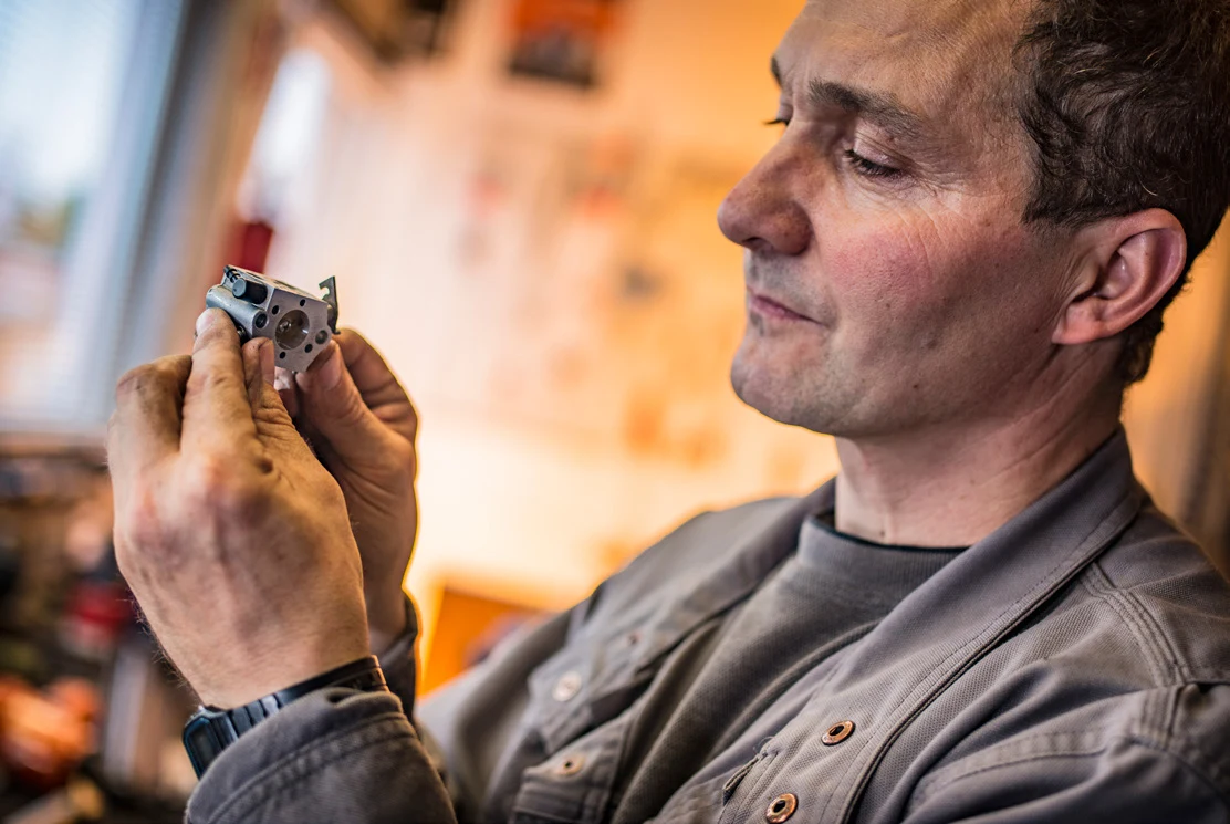 Ein Servicetechniker prüft in der Werkstatt ein kleines Bauteil in seinen Händen